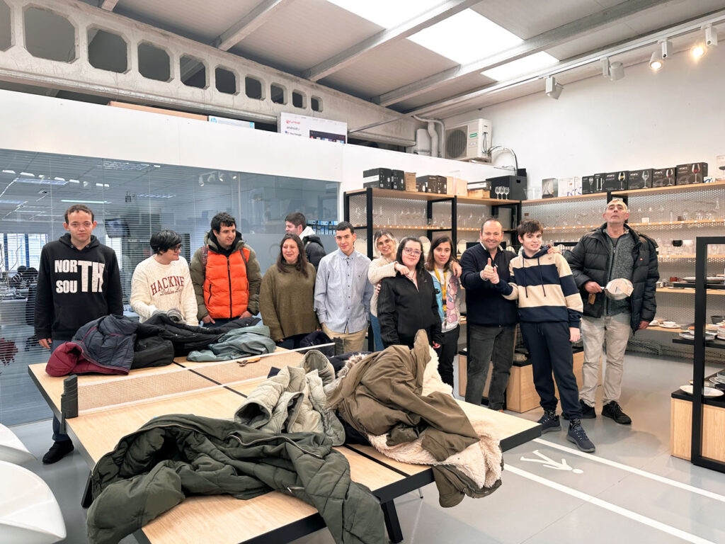 Foto de grupo de los usuarios y acompañantes de la Asociación Ámbar junto al equipo de roig en la zona de menaje del showroom de A Pobra do Caramiñal