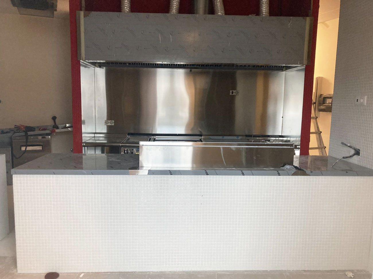 Instalación de campana extractora de acero inoxidable a medida sobre barra con frente de gresite blanco, cocina PPANG Marineda City A Coruña